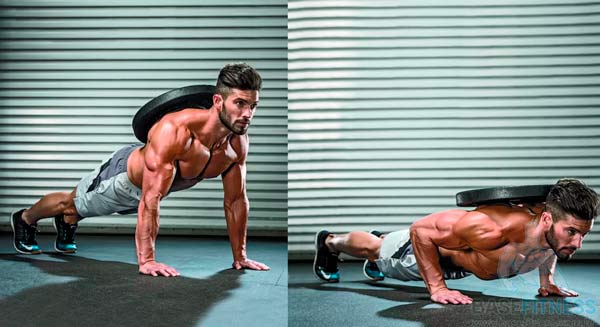 Homem fazendo flexões de braço com anilhas nas costas.