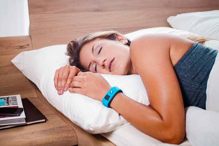 mulher dormindo na cama com relógio fitness