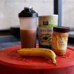 Alimentação Pós-Treino RECOMENDADA Segundo Pesquisas! Anilha com coqueteleira, aveia e pasta de amendoim, representando o ideal da alimentação pós-treino