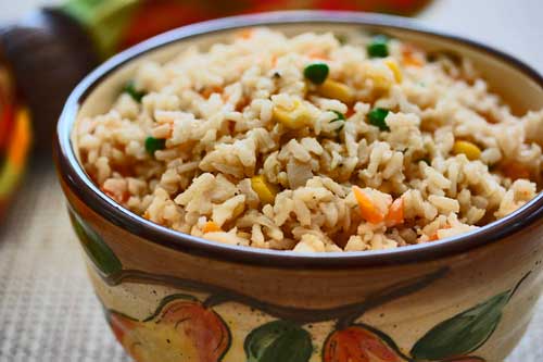 Arroz branco cozido com legumes em uma tigela funda.