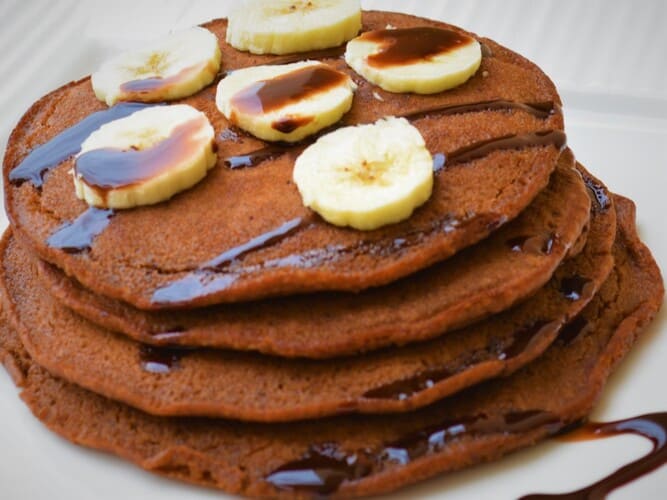 Panqueca de proteica de chocolate com calda e bananas em cima