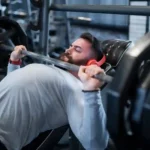 Treino de Peito e Tríceps: Focado em Hipertrofia (Ficha Completa) Homem fazendo supino no treino de peito e triceps