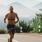 Quantas vezes correr na semana? Veja a frequência ideal! homem correndo na rua com morros ao fundo