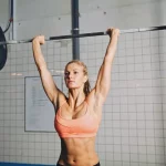 Desenvolvimento Militar: Execução correta, músculos trabalhados e 5 variações mulher realizando o desenvolvimento miitar com barra no box de crossfit