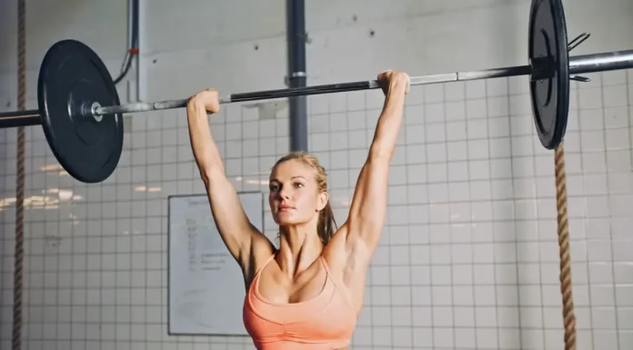 Desenvolvimento Militar: Execução correta, músculos trabalhados e 5 variações mulher realizando o desenvolvimento miitar com barra no box de crossfit