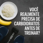 Prato de arroz branco e banana ao lado de tênis de corrida e halter sobre fundo escuro, com a frase 'Você realmente precisa de carboidratos antes de treinar?